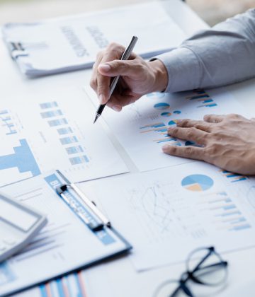 A female financier is reviewing company financial documents, monthly financial statement summary from the finance department. The concept of managing the company's finances for accuracy and growth.